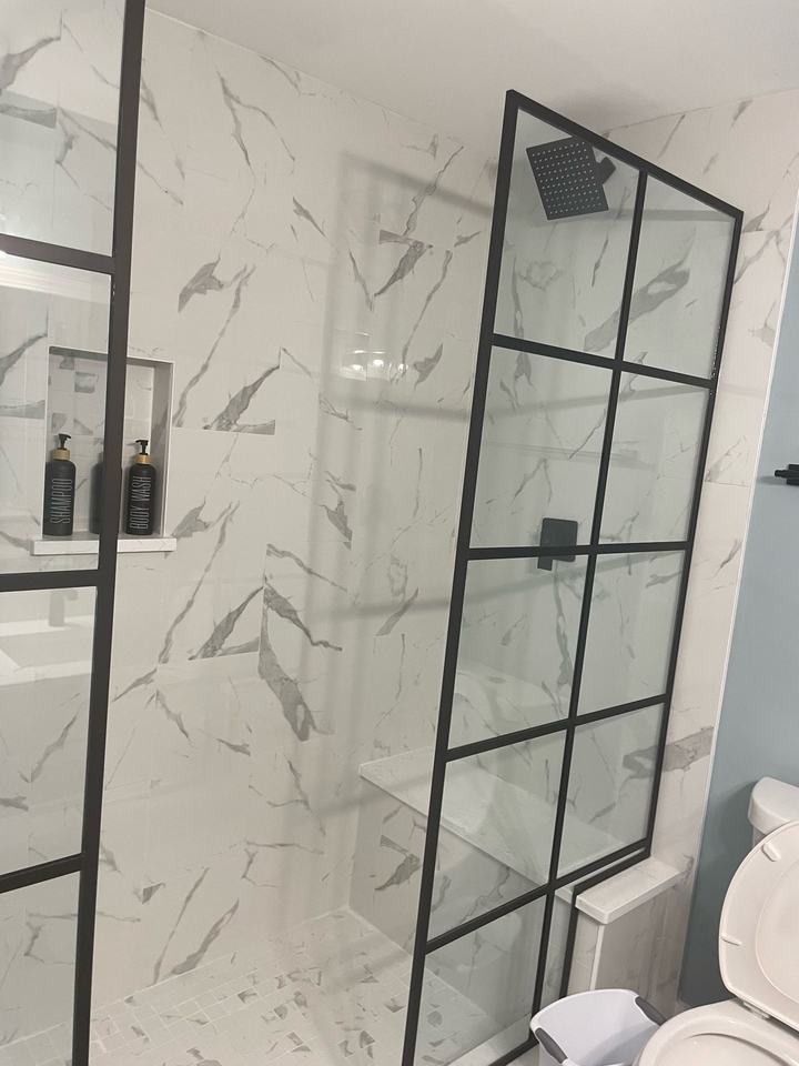 Marble-look shower with black grid glass panels
