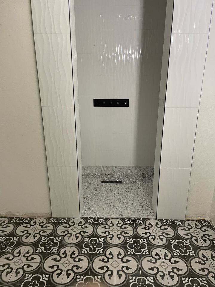 White wave tile shower with linear drain and patterned floor tile