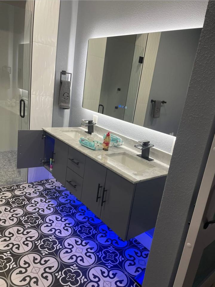 Floating gray double vanity with backlit mirror and patterned floor tile
