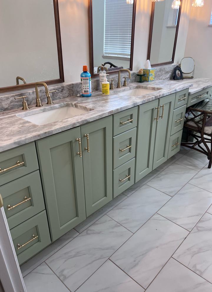 Sage green double vanity with stone counters and gold hardware